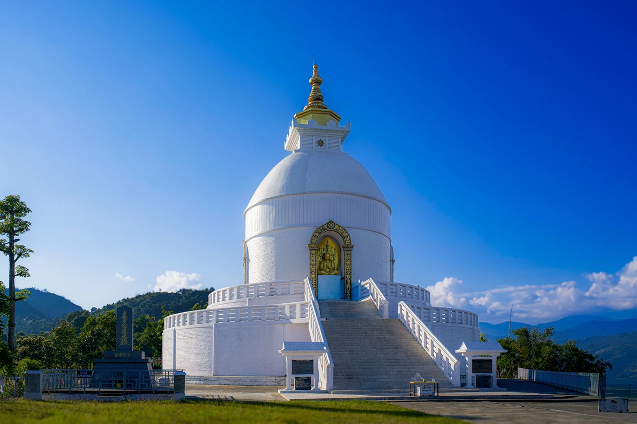 The brilliant white Shanti Stupa stands under a clear blue sky, overlooking the valley as one of the best places to visit in Pokhara.