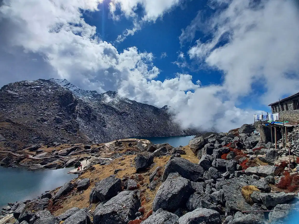 Large grey boulders overlook the deep blue Gosaikunda Lake under a dramatic sky, a key destination featured in our Langtang Gosaikunda Trek Guide.