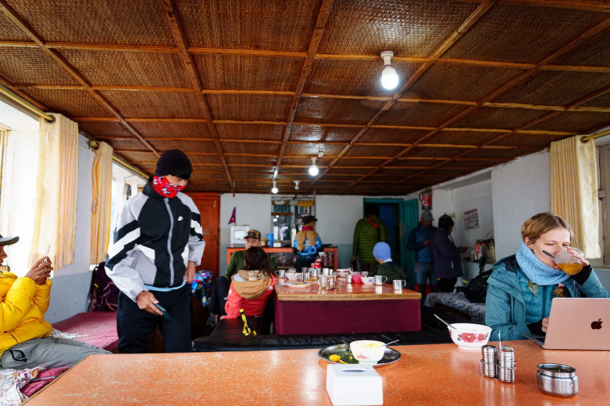 Trekkers gather inside a warm mountain teahouse to eat and rest. This Annapurna Circuit Trek Guide shows the communal dining experience found in local Himalayan lodges.