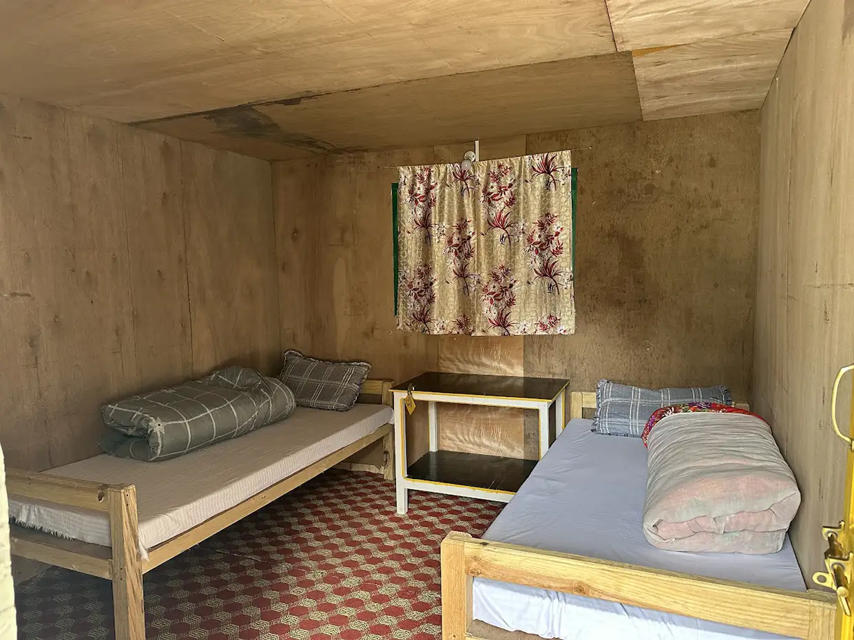Two simple wooden beds with quilts sit inside a rustic plywood teahouse room. A thorough Manaslu Trek Packing Guide helps travelers prepare for these basic mountain accommodations.