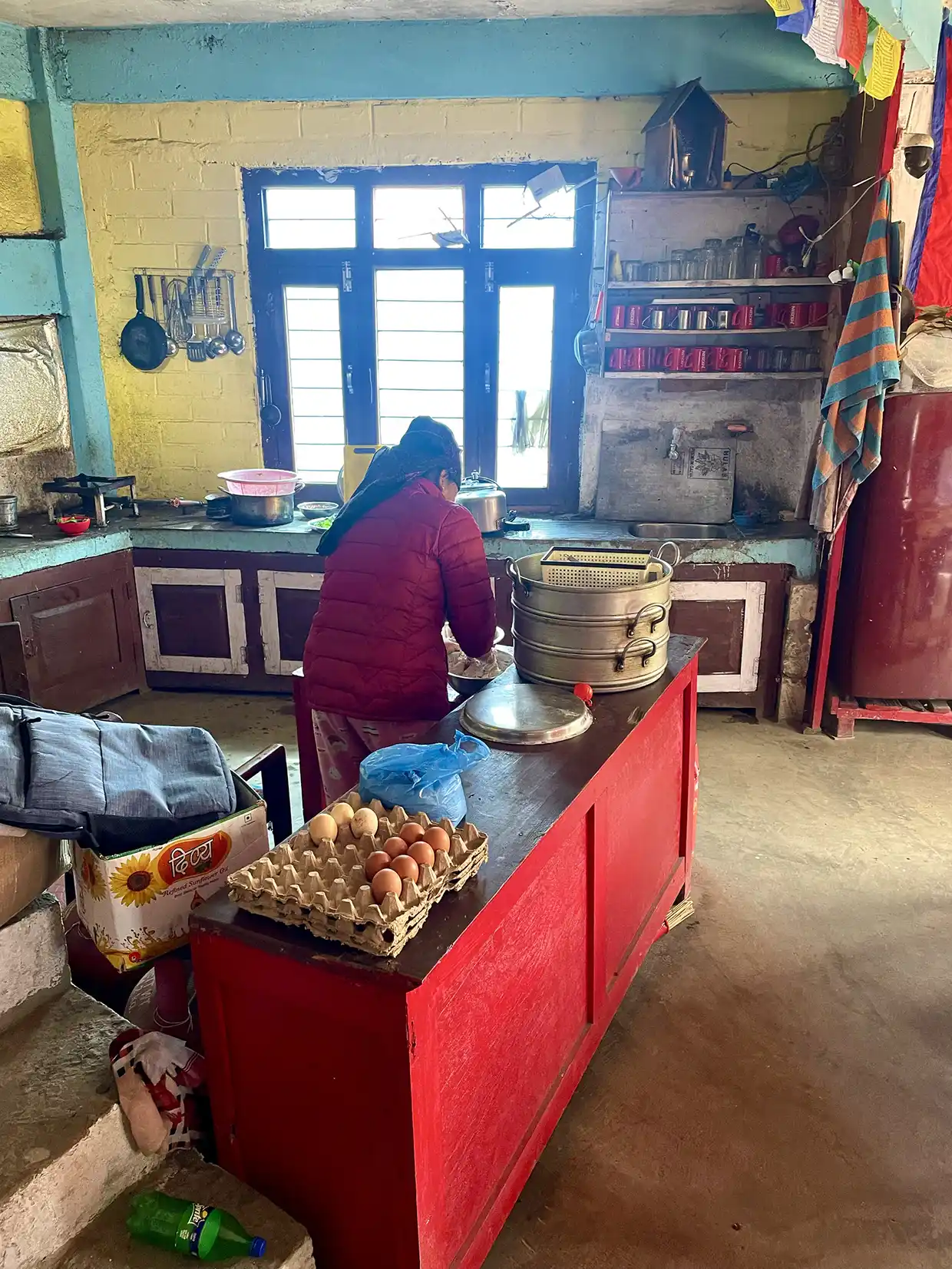 A local woman cooks inside a rustic teahouse kitchen along the mountain trail, preparing fresh food for travelers following a Manaslu Circuit Trek Guide.