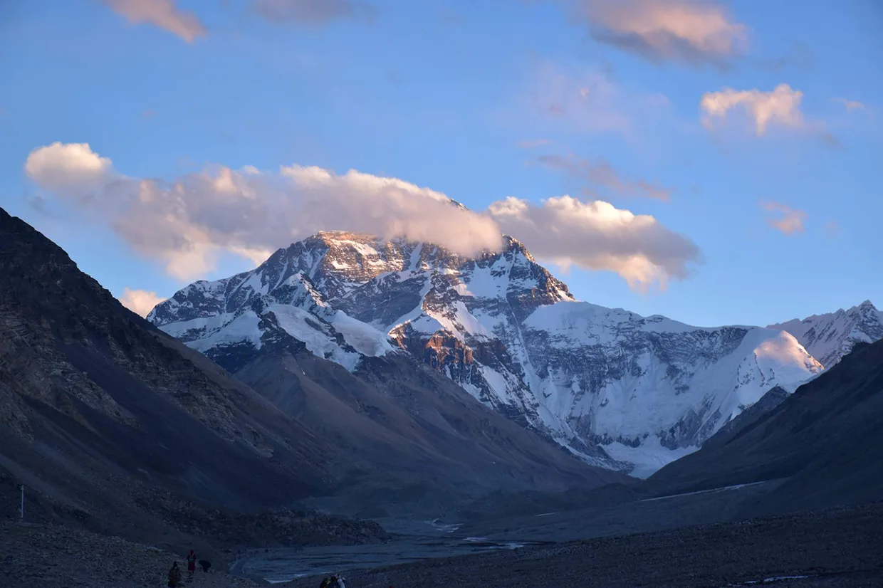 Clouds drift past the massive, snow-covered Dhaulagiri peak during sunset. This rugged Himalayan landscape is a centerpiece of any comprehensive Dhaulagiri Circuit Trek Guide.