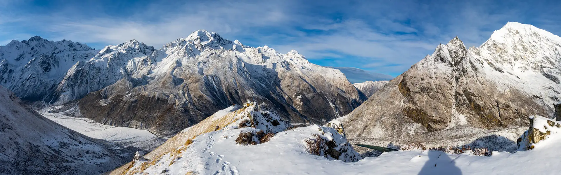 This wide panorama shows snowy Himalayan peaks and deep valleys in the Langtang region, illustrating the stunning scenery found when Hiking in Nepal by Month.