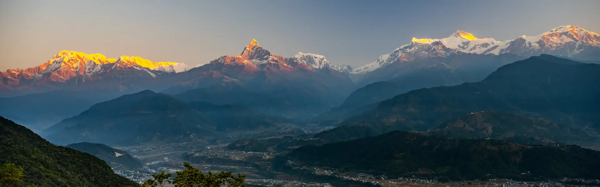 Golden sunrise light hits Machhapuchhre and the Annapurna peaks over the Pokhara Valley. Staying updated on Nepal Trekking Regulations helps protect travelers in these high-altitude areas.