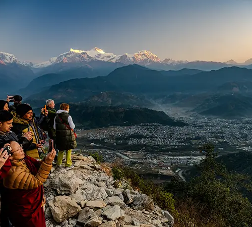 Trekkers stand on the summit of Poon Hill to photograph the sunrise over the Annapurna range. Following current Nepal Trekking Regulations is vital for a safe mountain experience.