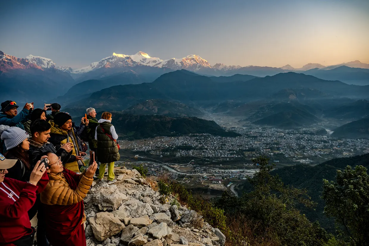 A group of travelers captures the sunrise over a massive valley and snow-covered peaks during their Khopra Ridge Trek adventure in Nepal.