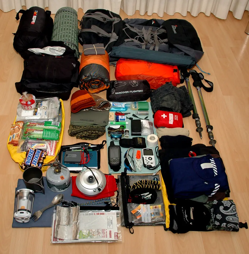 A detailed overhead view of diverse hiking gear for the Annapurna Base Camp Trek Packing List, including backpacks, sleeping bags, medical supplies, cooking equipment, snacks, and clothing.