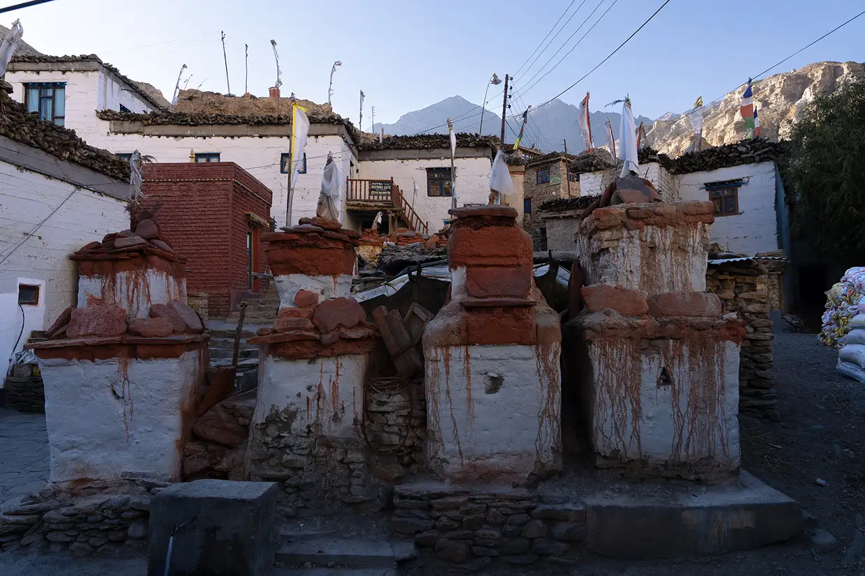 Traditional Buddhist chortens stand in a rustic mountain village under a blue sky during a premium Upper Mustang Jeep Tour in Nepal.