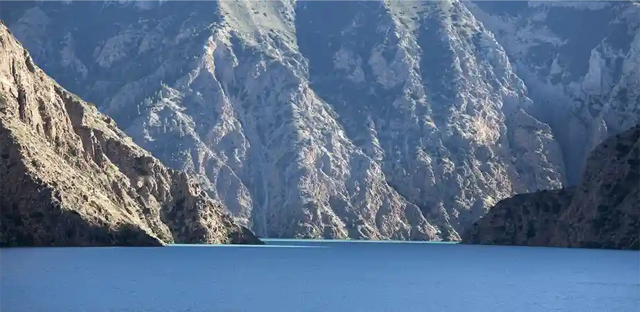 Vibrant blue waters of Phoksundo Lake surrounded by towering rocky cliffs experienced during the Shey Phoksundo Lake Trek